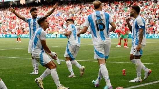 Olympic football tournament Morocco vs Argentina match controversy VAR decision fan invasion dramatic football match Argentina's Cristian Medina disallowed goal chaotic football match Saint-Etienne football match Morocco fans storm pitch objects thrown players Morocco's Soufiane Rahimi Achraf Hakimi assist penalty goal Giuliano Simeone Javier Mascherano Argentina squad Julian